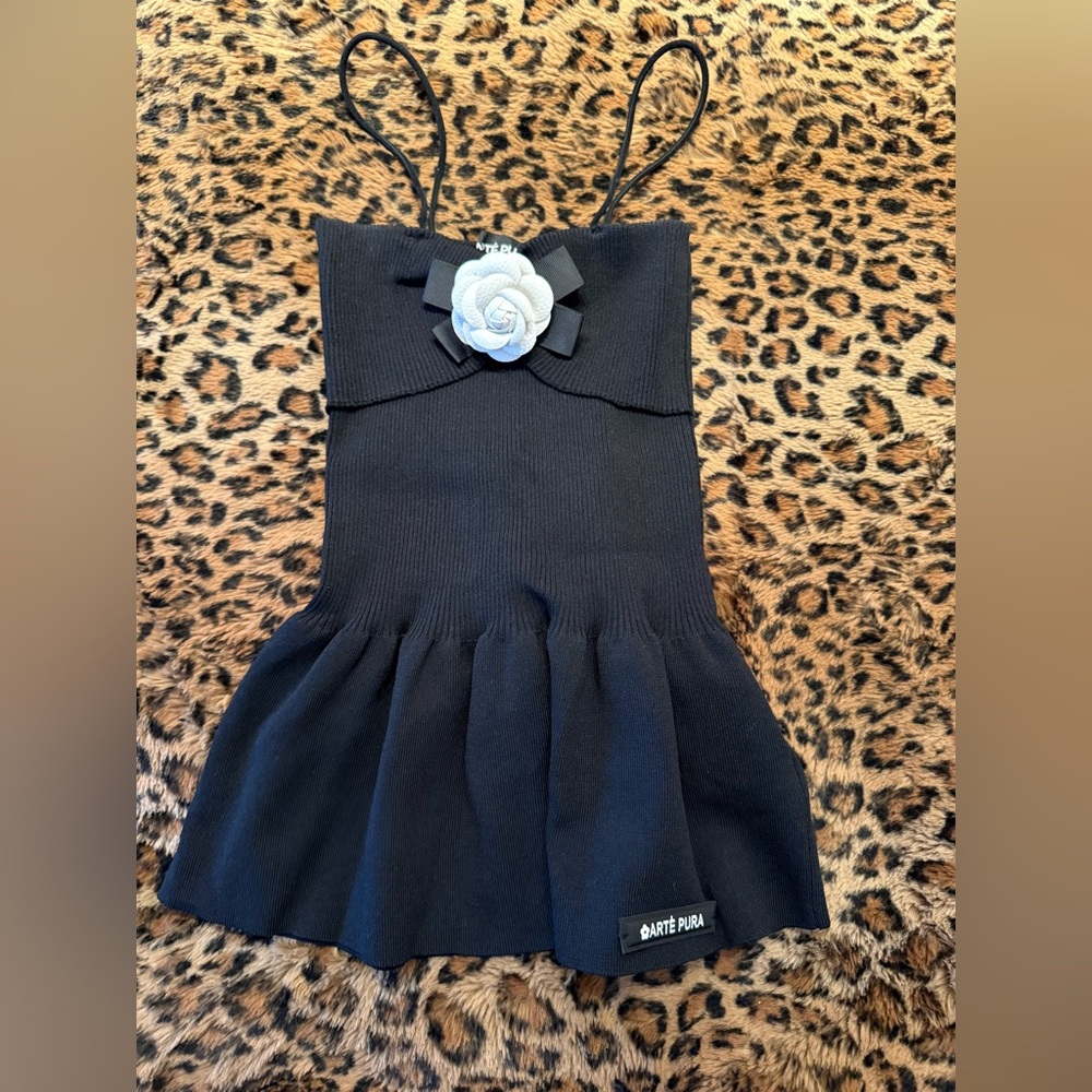 Spaghetti strap knit black top w/ white flower. Fitted w/ a slight flair.